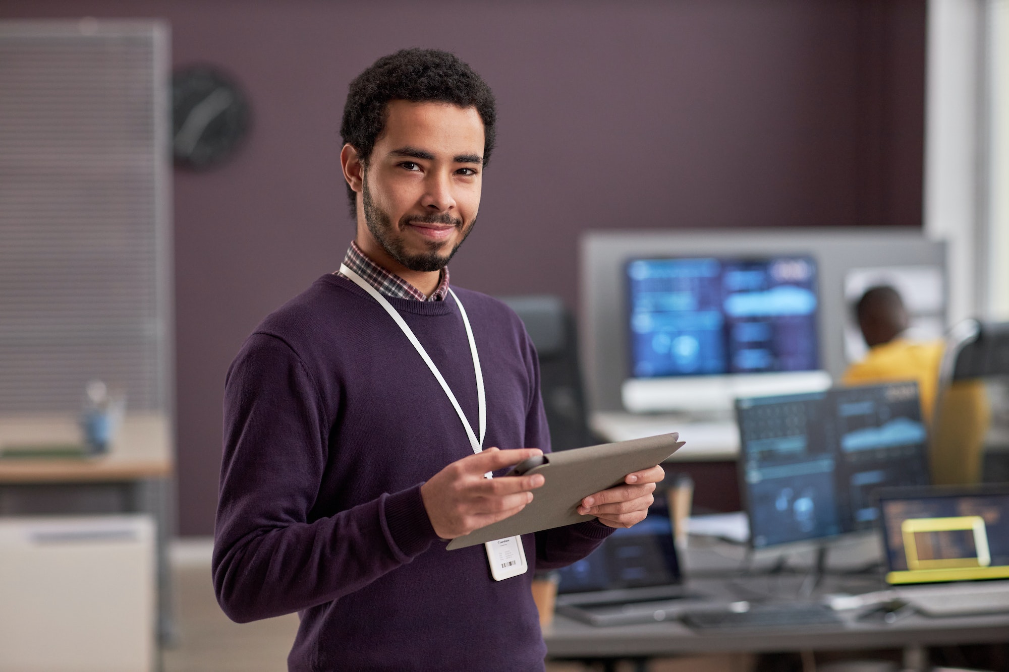 Smiling software engineer holding digital tablet while standing in tech office